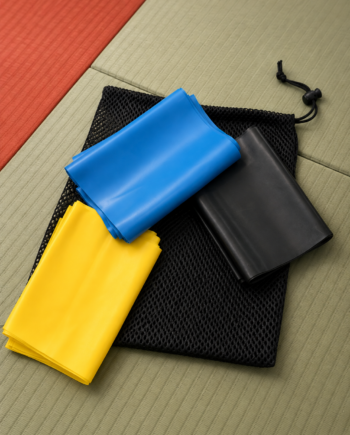 Bandes élastiques d'entraînement jaune, bleue et noire sur un tatami de judo